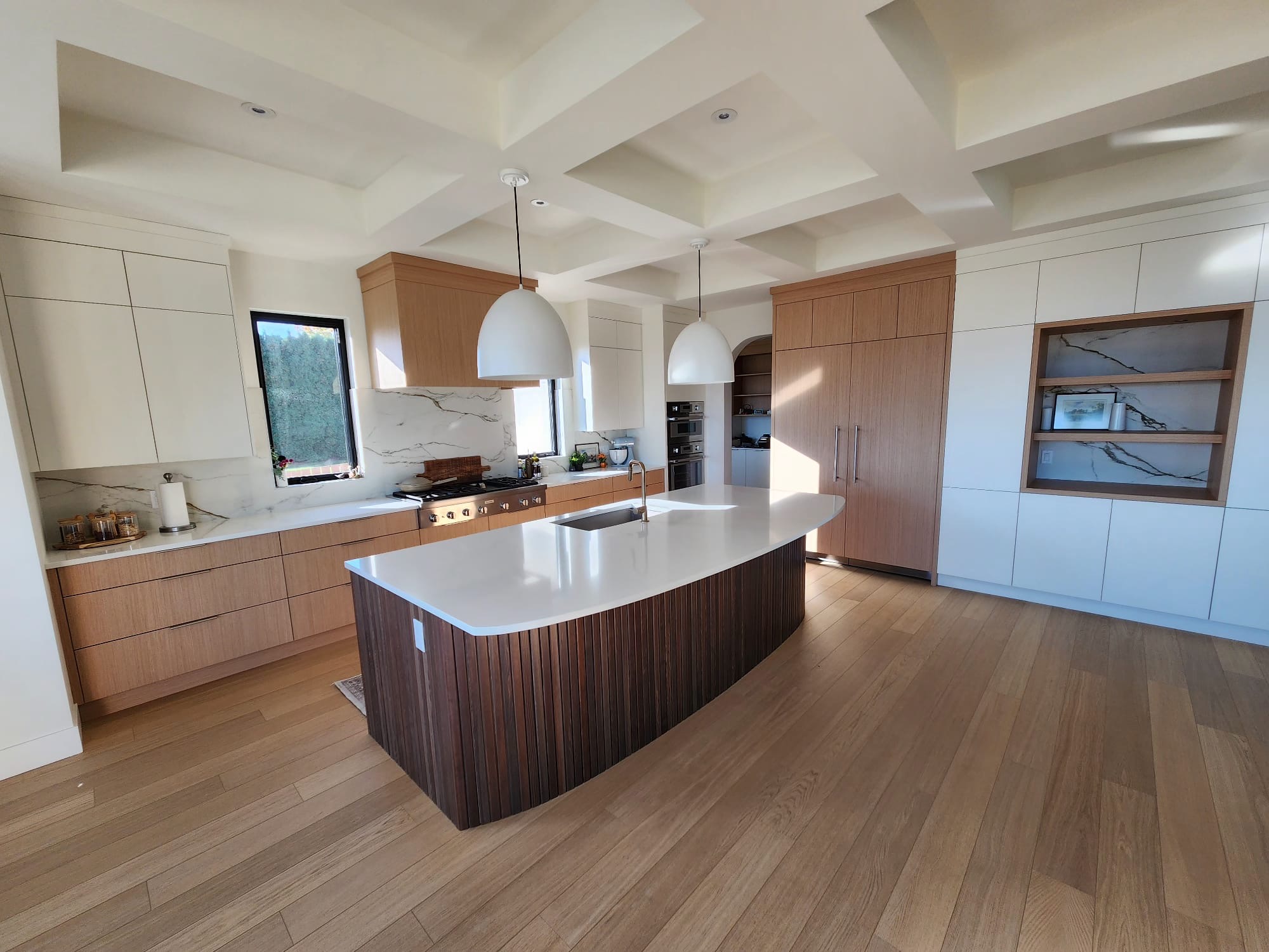 Modern kitchen with wood and white cabinetry, large island, and pendant lights